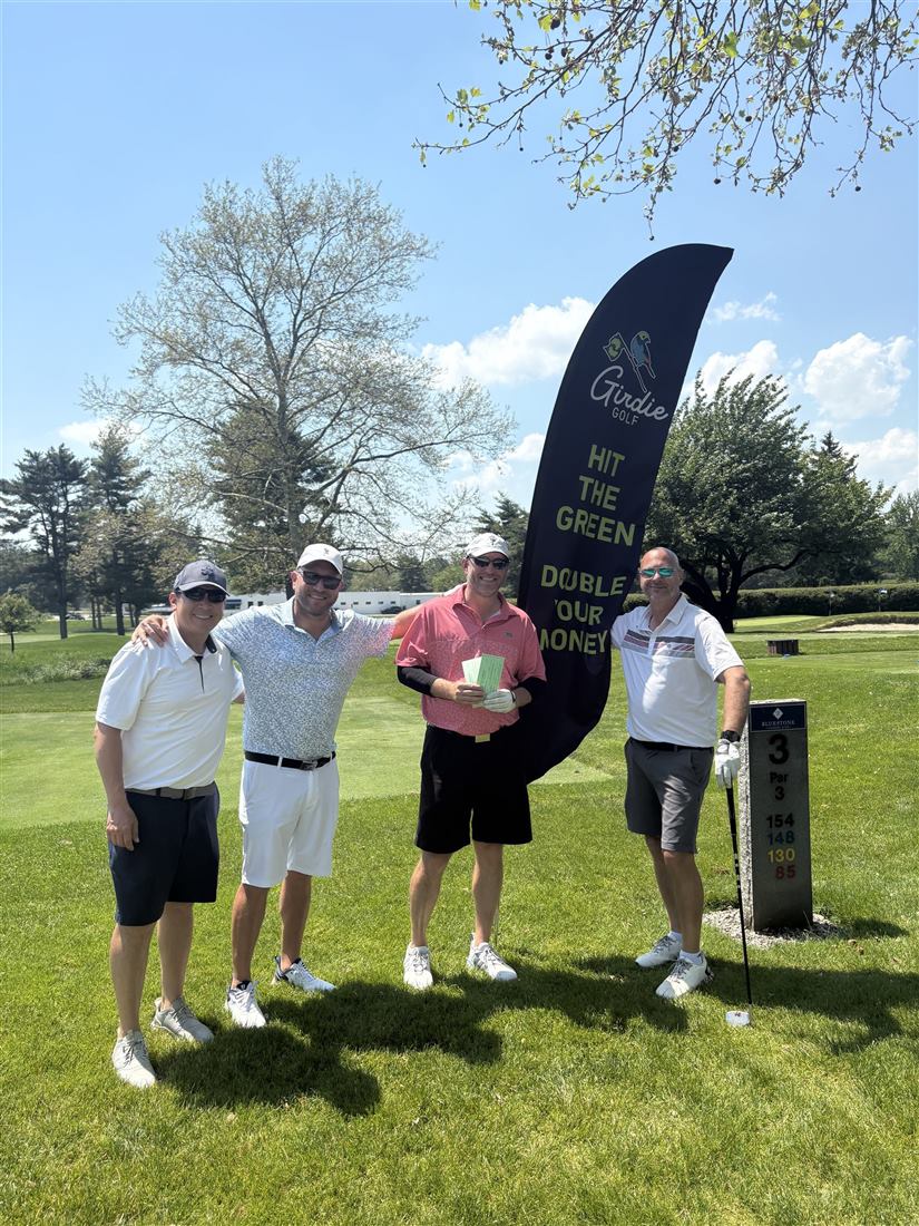 A foursome at an outing holding up their Girdie Golf gift card